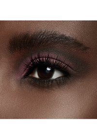 Close-up van een donkerbruine oog met dikke, lange wimpers en een smokey eye make-up met roze en donkere tinten op het ooglid. Glad huidtextuur.
