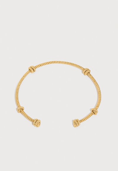 Βραχιόλι από χρυσό στριφτό σχοινί με πέντε κόμπους σε ίση απόσταση, ανοιχτού σχεδιασμού, σε λευκό φόντο.