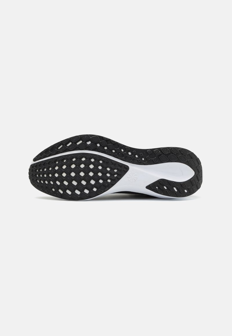 Suela de zapatilla negra con un patrón texturizado, que presenta recortes en forma de diamante, y un acento de entresuela blanca. Material de goma suave en general.