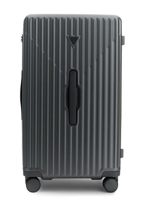 Valise rigide de couleur gris foncé, dotée de rainures verticales, d'une poignée centrale et de quatre roues pour la mobilité.