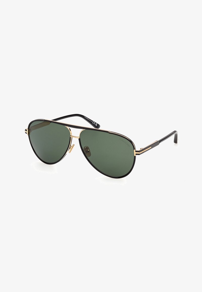 Lunettes de soleil aviateur en métal noir et or avec verres verts foncés et plaquettes de nez réglables, légèrement inclinées vers la droite sur fond blanc.
