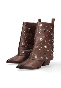 Bruine leren enkelboots met puntige neuzen en blokhakken, versierd met verschillende zilveren metalen studs en geometrische vormen.