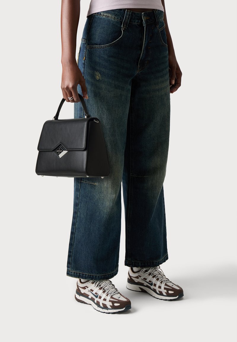 Zwarte synthetische handtas met een gestructureerd ontwerp en opvallende diamantaccent. Draagt met loszittende vervaagde blauwe jeans en multkleurrige sneakers.