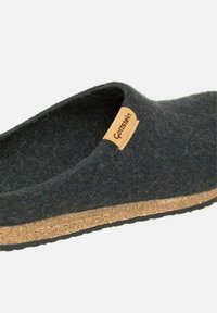 Chausson en feutre noir avec une semelle en liège naturel. Il est doté d'une étiquette en cuir de marque et d'une tige lisse et texturée. Sa forme arrondie assure un confort optimal.