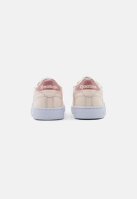 Reebok sneakers in light pink leather with a textured finish, featuring a white rubber sole and logo at the heel in pink.