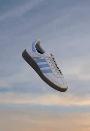 Men's athletic sneaker, white leather with light blue accents, suede sections, rubber sole, features three stripes and a logo.