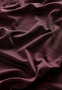 Bordeauxrood textiel met een zachte val en subtiele lijnen, met rijke kleurvariaties en een gladde afwerking.