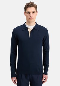 Polo de manga larga en color navy con cuello color crema y una botonadura de tres botones. Tejido de punto suave, con un pequeño acento de logo.