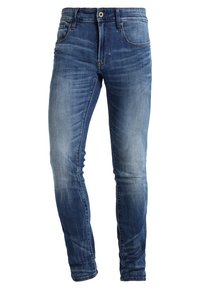 Jeans de denim azul ajustados con un acabado desgastado. Cuenta con cinco bolsillos, pasadores para cinturón y un cierre de botón de metal en la cintura.