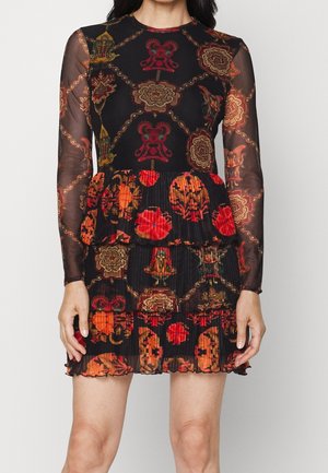 Vestido negro transparente de manga larga con patrones florales y geométricos en rojo y naranja, con una falda de volantes plisada por encima de la rodilla.