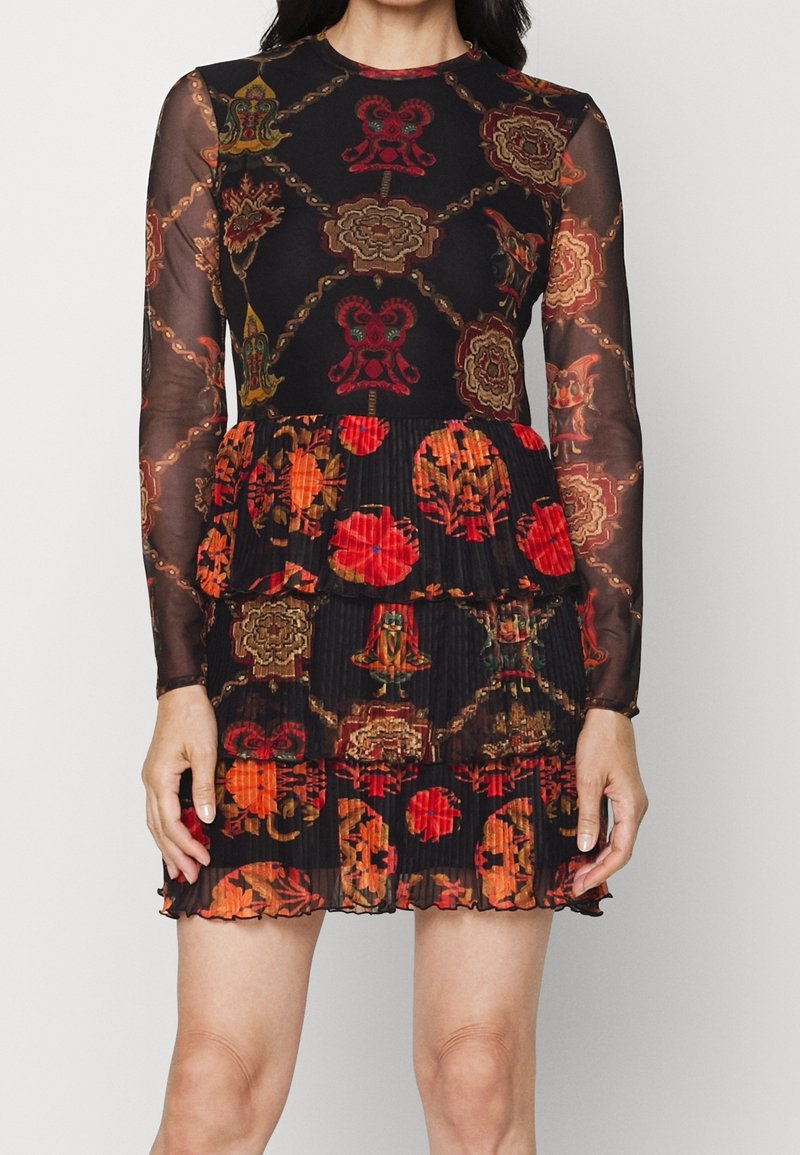 Robe noire transparente à manches longues avec motifs floraux et géométriques rouges et orange, avec une jupe à volants plissée au-dessus du genou.