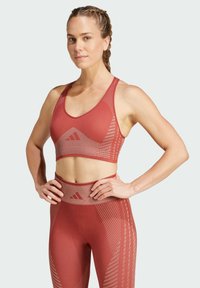 Red athletic crop top with a racerback design. Features textured stripes and logo. Paired with matching high-waisted leggings.