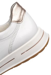 White sneaker heel with metallic bronze accent, textured white sole with bronze stripe, and visible stitching on smooth leather upper.