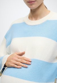 Viegls, svītrains džemperis ar maiņstrīpām gaismazilā un baltā krāsā, ar ribotu apkakli un aprocēm. Mīksts, teksturēts audums.