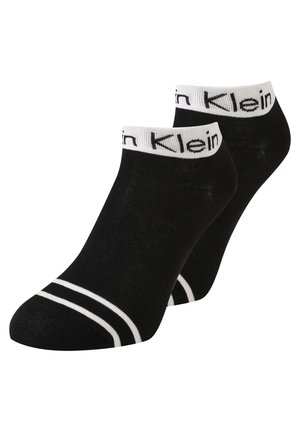 Chaussettes noires à la cheville en tissu doux, avec un bandeau logo blanc en haut et des rayures blanches sur le bout.