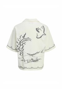 Chemise à manches courtes en tissu crème clair avec des illustrations détaillées en gris de montagnes, d'arbres et d'un oiseau dans le dos.