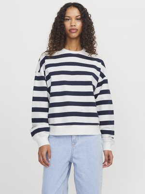 Marineblauwe en witte gestreepte sweatshirt met een ronde hals, verlaagde schouders en ribgebreide manchetten. Gecombineerd met lichtblauwe denim jeans.