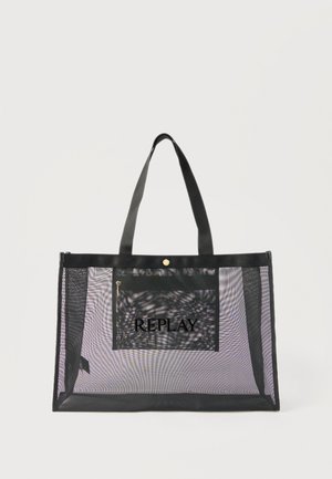 Svart, gjennomsiktig mesh-handlenett med to håndtak, frontlomme med glidelås og "REPLAY"-logo på lommen mot ensfarget bakgrunn.