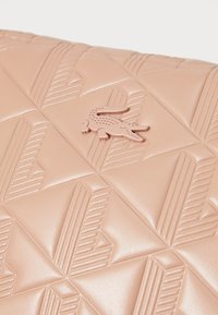Borsa in pelle rosa pallido con un motivo geometrico in rilievo, dotata di un piccolo logo a forma di coccodrillo nell'angolo inferiore.
