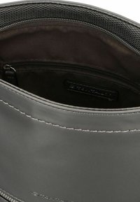 Graue, lässige Tasche mit glattem Äußeren, Reißverschlussverschluss, Futter aus Stoff und einer Innenfach mit Reißverschluss. Dezente Steppnähte entlang der Kanten.