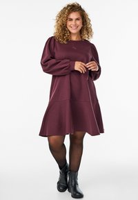 Bordeaux pullover jurk met pofmouwen en een uitlopend zoom. Gemaakt van zachte stof, met een tonale geborduurde logo op de borst.