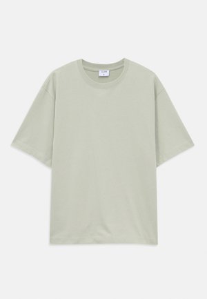 Camiseta de algodón de corte holgado, de manga corta y color verde claro, con cuello redondo, dispuesta sobre fondo blanco.
