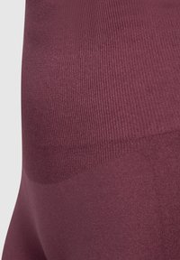 Burgunderfarbene nahtlose Leggings mit einer gerippten Textur am Bund und einem glatten Finish, entworfen für Komfort und Flexibilität.