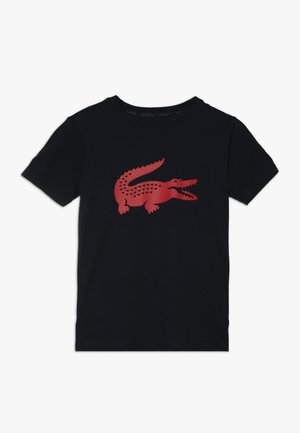 Czarna koszulka z krótkim rękawem z dużym czerwonym stylizowanym wizerunkiem krokodyla na środku przodu.