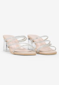 Sandalias con tacón transparente que cuentan con una base nude, correas transparentes adornadas con diamantes de imitación plateados y un diseño minimalista.