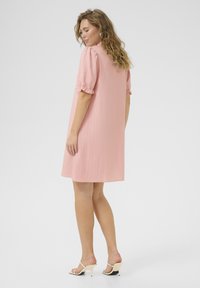 Robe rose à manches courtes en tissu texturé, avec des manches bouffantes et une coupe décontractée, au-dessus du genou avec une silhouette droite.