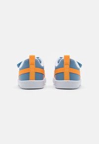 Zapatillas deportivas en azul y blanco con correas de acento en naranja. Cuentan con una suela de goma lisa, tela texturizada y una lengüeta en la parte posterior.