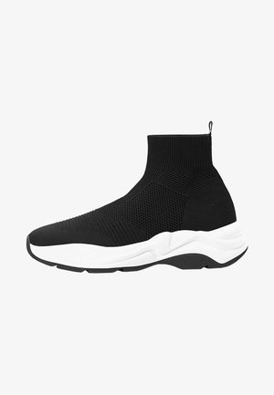 Basket chaussette montante noire avec dessus en maille, semelle blanche épaisse et languette au talon, vue du côté extérieur.