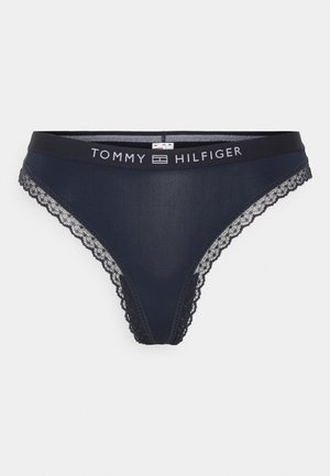 Marineblauwe thongonderbroek met kantafwerking en een zwarte tailleband met het "TOMMY HILFIGER" logo in het wit. Glad stoffen ontwerp.