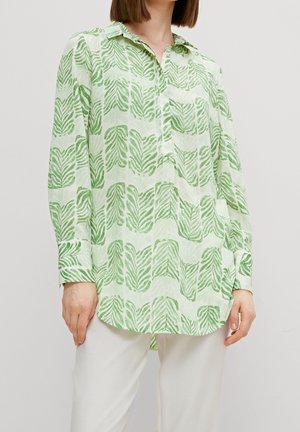Chemise à manches longues à motif de feuilles vertes, fabriquée en tissu léger, avec un col et un ourlet arrondi.