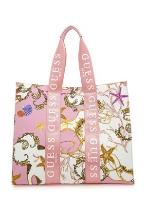 Roze-witte strandtas met schelp- en zeesterrenpatronen, met roze hengsels met het opschrift "GUESS BEACH" in witte letters.
