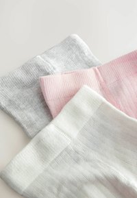 Tre paia di calzini a coste in grigio chiaro, rosa e bianco. Ognuno presenta una texture morbida e dei polsini a contrasto.