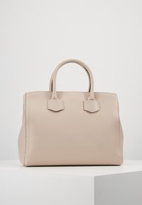 Beżowa skórzana torebka o fakturowanym wykończeniu, w wyraźnym prostokątnym kształcie, z dwoma krótkimi uchwytami i subtelnymi bocznymi akcentami.