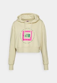 Hoodie accorciato, beige chiaro, realizzato in tessuto morbido. Presenta una grande grafica multicolore con "THE NORTH FACE" in accenti verdi e rosa.