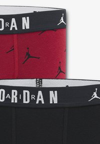 Δύο ζευγάρια ανδρικά μπόξερ: ένα κόκκινο με μαύρο μοτίβο λογότυπου Jordan και ένα μονόχρωμο μαύρο. Και τα δύο έχουν ελαστική μέση με κείμενο "JORDAN".
