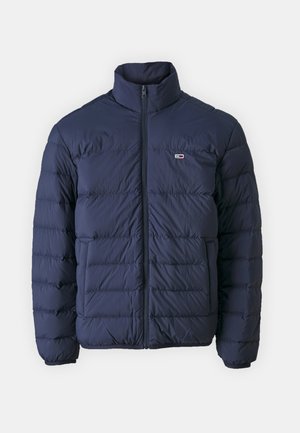 Navy puffer jacket with a high collar, quilted design, front zipper, and small logo accent on the chest. Smooth, lightweight material.