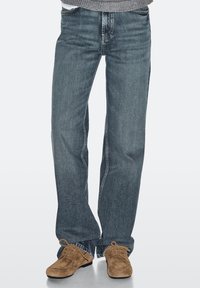 Lyseblå denimjeans med lige ben, synlige sømme og lynlås foran. Kombineret med brune ruskindssko.