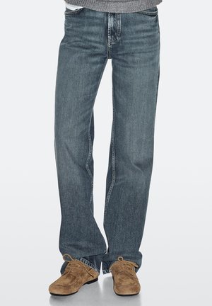 Lyseblå denimjeans med lige ben, synlige sømme og lynlås foran. Kombineret med brune ruskindssko.