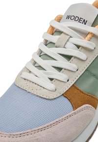 Zapatillas con paneles de malla, ante y cuero en azul claro, verde, marrón y beige. Presentan cordones blancos y un logo de "WODEN" en la lengüeta.