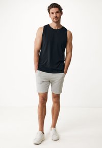 Svart ärmlös linne, grå shorts och vita sneakers. Linnan är gjord av mjukt tyg, shortsen är lätta med en avslappnad passform.