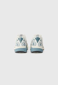 Sport shoes featuring a white upper with light blue accents, textured heel, and a cushioned blue sole. Back view highlights design details.