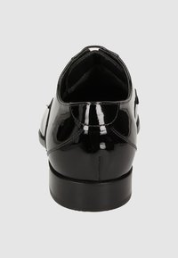 Zwarte gepatenteerde leren schoen met een gepolijste afwerking, ronde hak, gebogen kraag en minimale stiksels. Overal een gladde textuur.