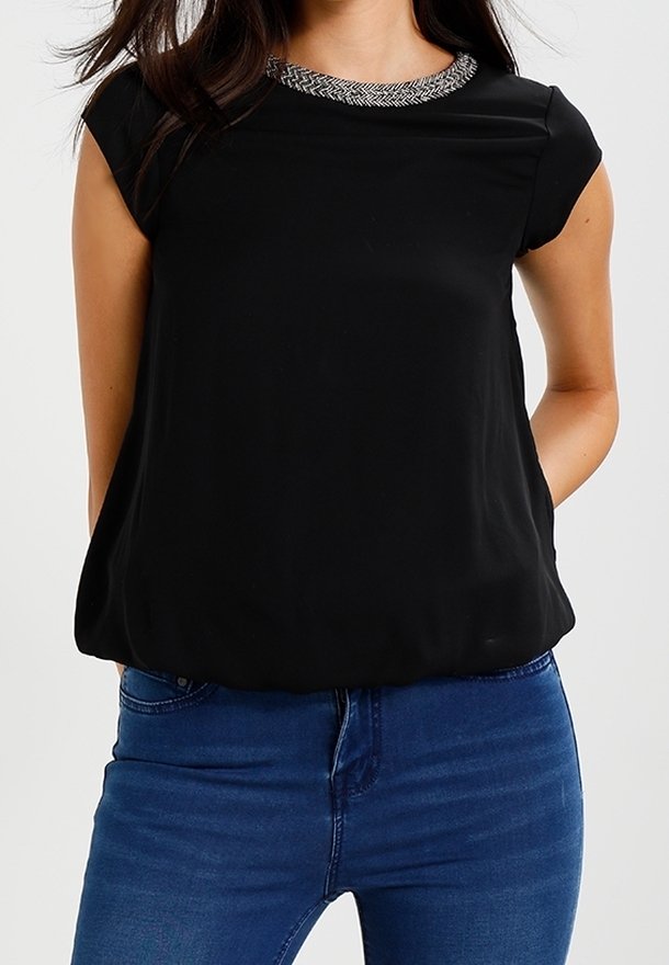 Black short-sleeved top with a textured silver beaded neckline. Loose fit and soft fabric, paired with blue denim jeans.