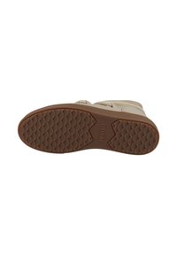 Calzado beige con una suela de goma texturizada. Presenta un dibujo de tread y detalles de la marca en la suela. La parte superior muestra elementos de diseño casual.