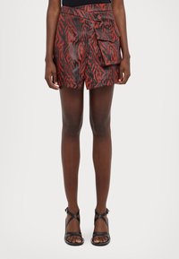 Shorts à motifs rouges et noirs avec taille haute, fermeture à bouton à l'avant et poche latérale. Fabriqués dans un tissu lisse et texturé.