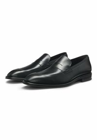 Mocassins en cuir noir avec une finition lisse, un bout légèrement pointu, des accents cousus et un talon bas.